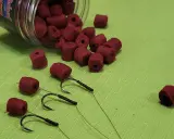 Czerwone kulki zanętowe i haczyki wędkarskie. Różne rozmiary haczyków wędkarskich i kulek.