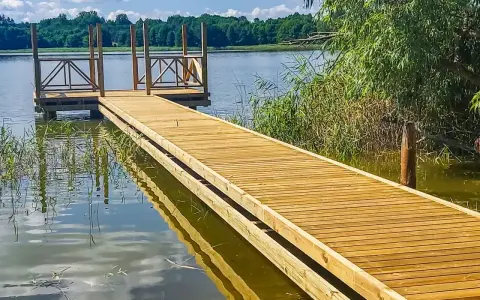 Drewniane pomosty nad jeziorem, idealne na letnie wypady nad wodę. Stawy komercyjne zapraszają do relaksu.