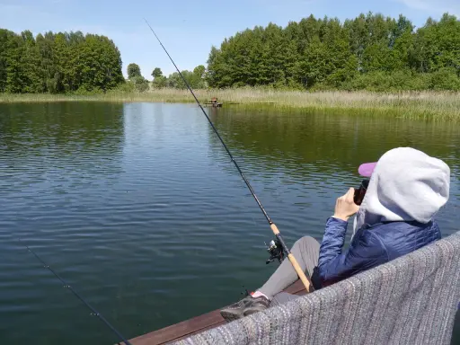 Osoba łowi ryby nad jeziorem Tuchlin, ciesząc się spokojem i pięknem natury.