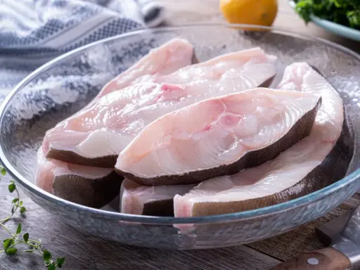 Świeże kawałki halibuta w szklanej misce, gotowe do przyrządzenia. Zapach halibuta na jakie ryby?