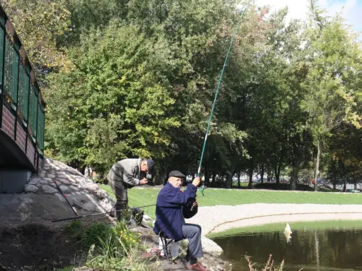 Dwóch wędkarzy łowi ryby nad jeziorem w Chojnicach. Jeden z nich właśnie wyciąga zdobycz.