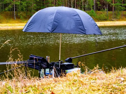 Parasol na ryby chroniący sprzęt wędkarski nad jeziorem.