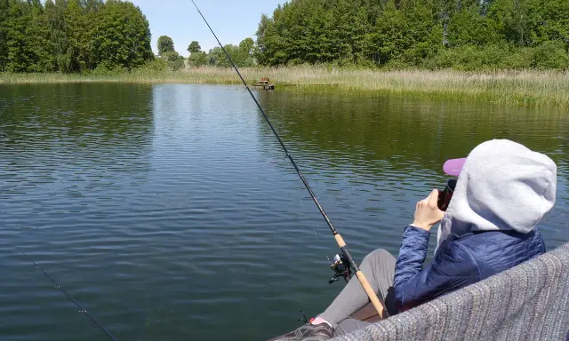 Osoba łowi ryby nad jeziorem Tuchlin, ciesząc się spokojem i pięknem natury.