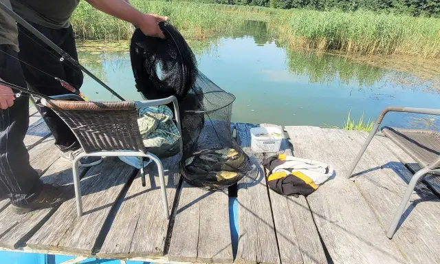 Udany połów na łowisku Chojnca. W siatce kilka ryb, obok wędki i krzesła.