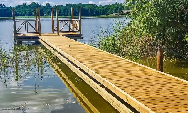 Drewniane pomosty nad jeziorem, idealne na letnie wypady nad wodę. Stawy komercyjne zapraszają do relaksu.
