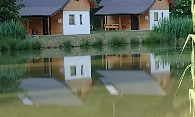 Urokliwe łowisko z domkami letniskowymi, których odbicia tańczą na spokojnej tafli wody.