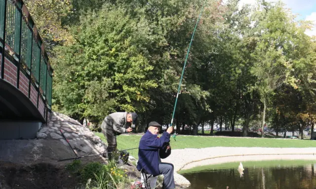 Dwóch wędkarzy łowi ryby nad jeziorem w Chojnicach. Jeden z nich właśnie wyciąga zdobycz.
