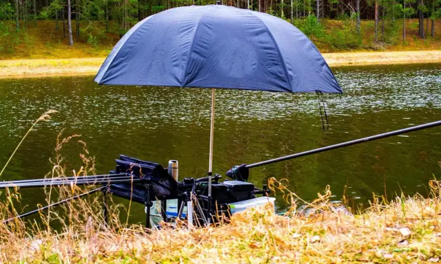 Parasol na ryby chroniący sprzęt wędkarski nad jeziorem.
